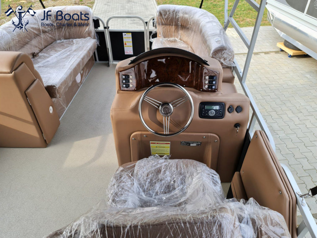 Boot Detailansicht mit Fokus auf Steuerstand mit Lenkrad, Marineradio, Schaltpanel und Windshield.